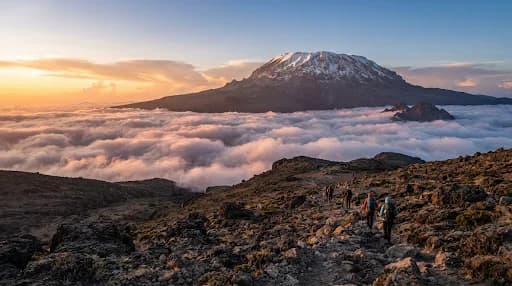 Majestic view of Mount Kilimanjaro summit glaciers above a thick sea of sunset clouds seen from the scenic Lemosho route high altitude alpine desert.